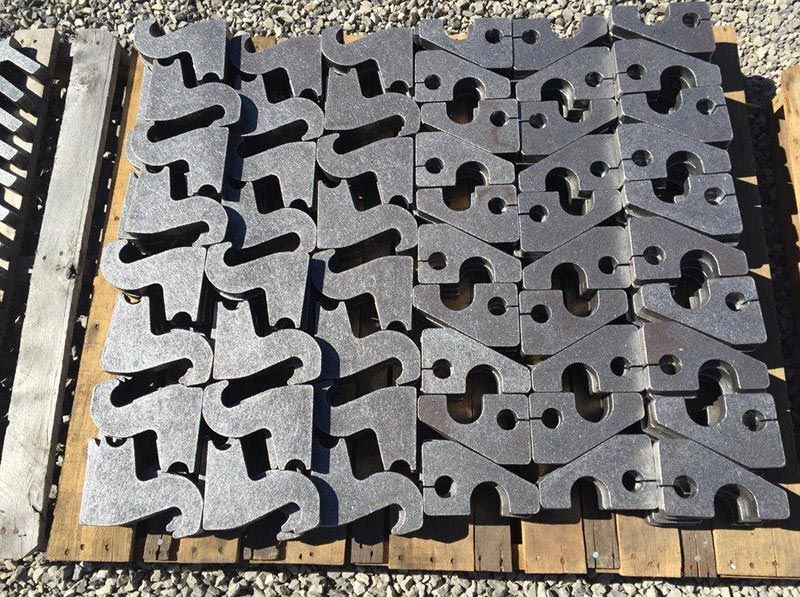 Stacks of gray interlocking concrete paving blocks on a wooden pallet in sunlight