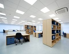 Bright office space with desks, shelving, and recessed lighting.