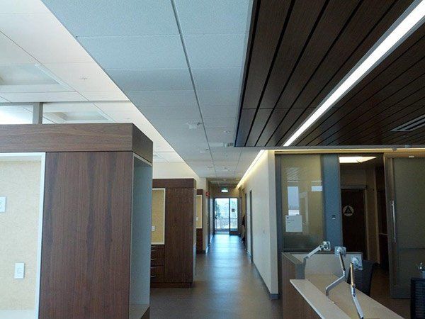 Hallway with brown wood paneling on the ceiling and side walls, illuminated with white lights.
