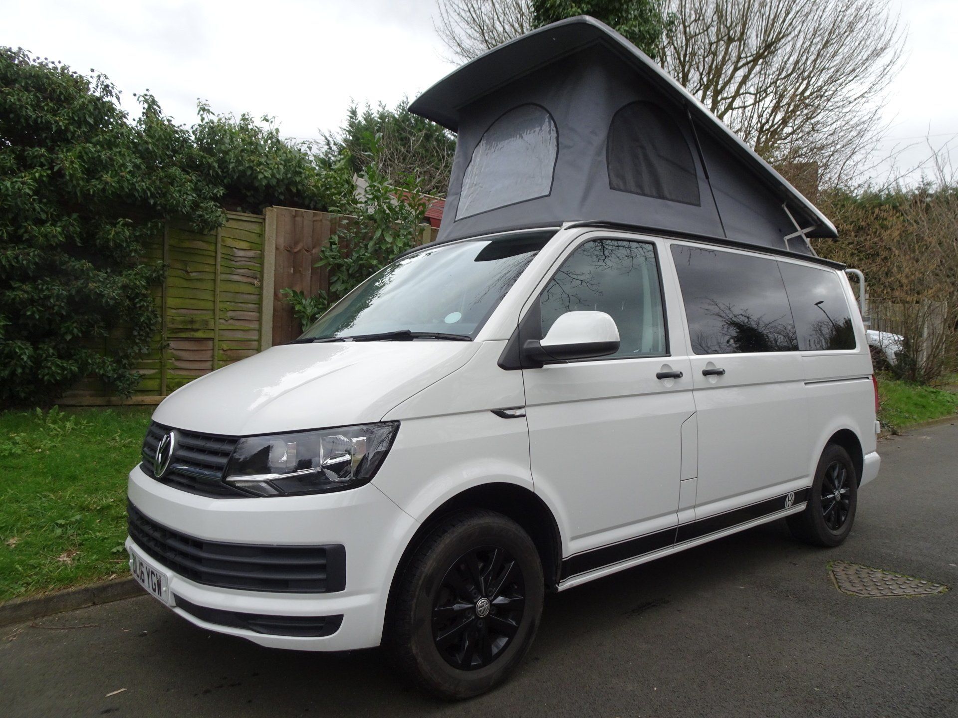 a white van with a pop up roof is parked on the side of the road .