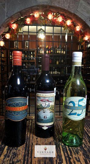 Hay tres botellas de vino sobre una mesa de madera.