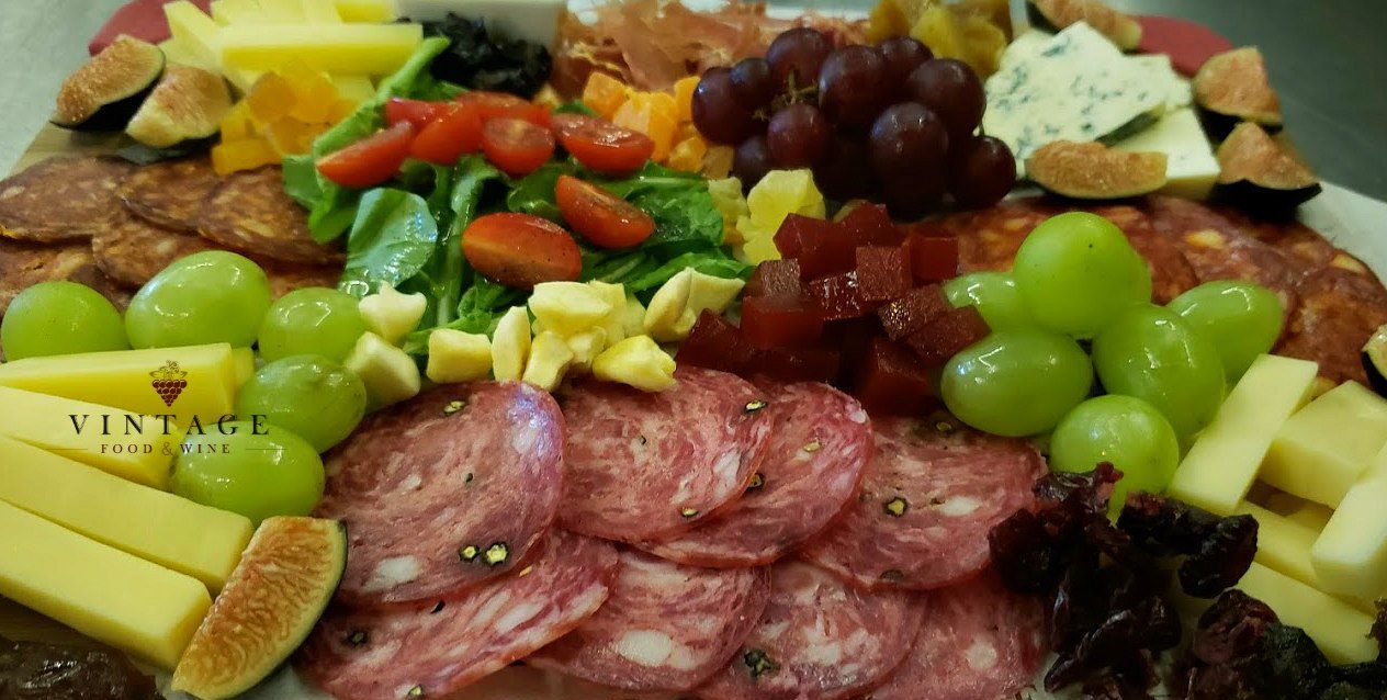 Un plato de comida con carne, queso, uvas e higos sobre una mesa.