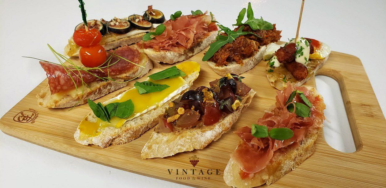 Una tabla de cortar de madera cubierta con una variedad de sándwiches y aperitivos.