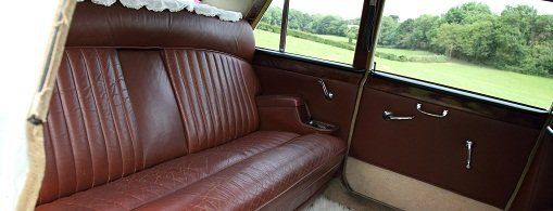 The interior of a car, furnished in wood and red leather