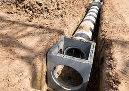 a concrete pipe is being installed in a trench .