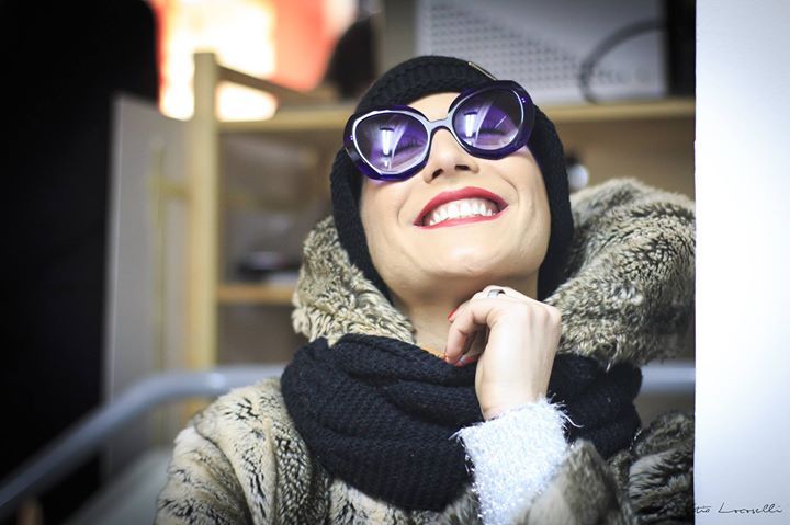 Una donna che indossa occhiali da sole e una sciarpa sorride