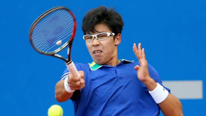 Un uomo che indossa occhiali e una maglietta blu sta giocando a tennis