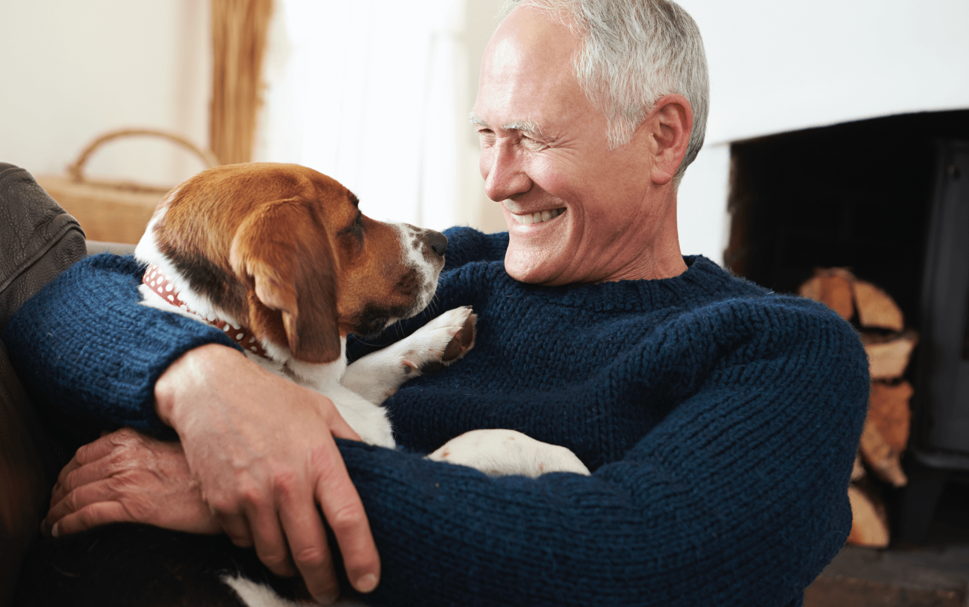 A man is sitting on a couch holding a dog.