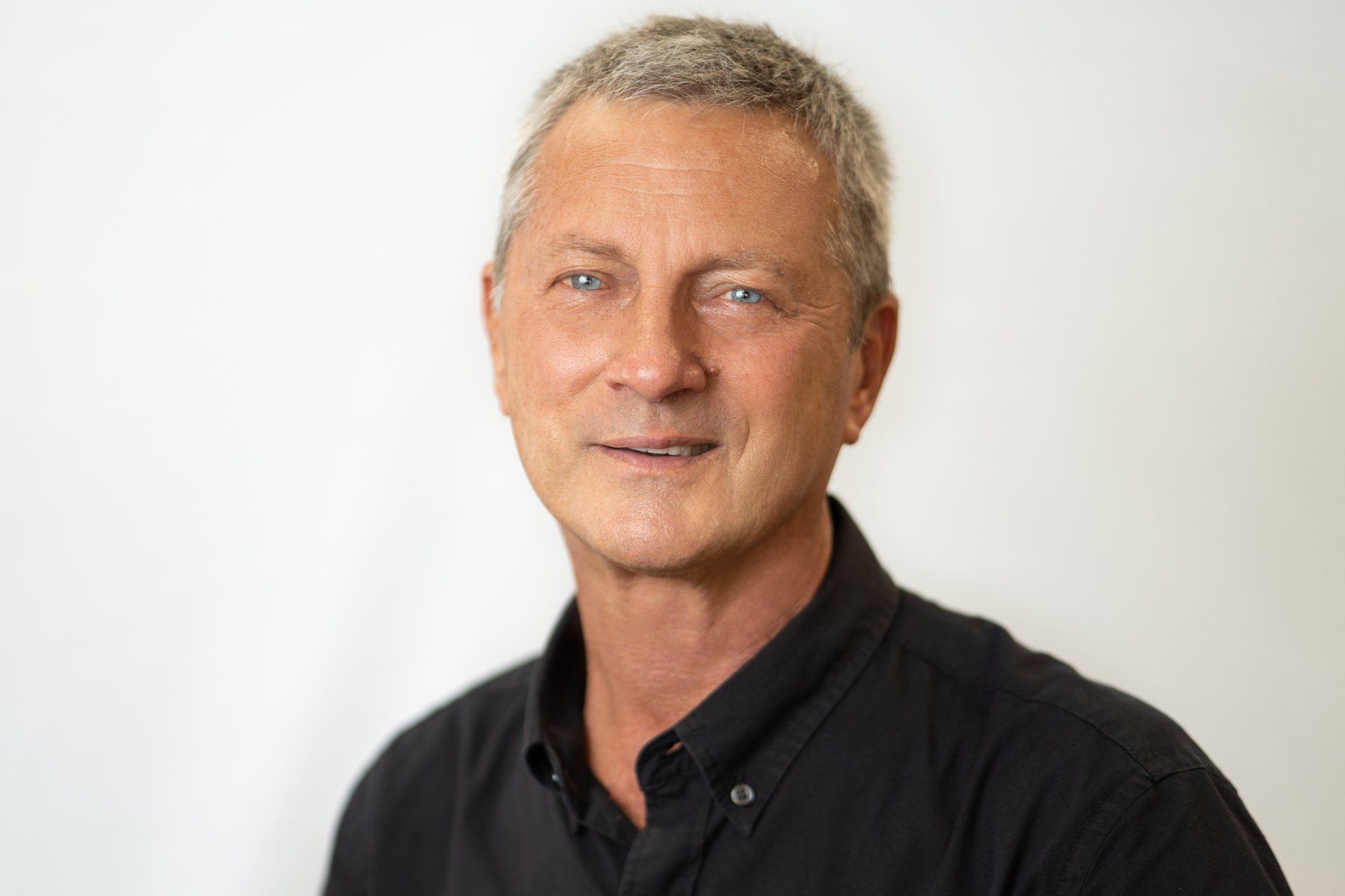 a man in a black shirt is smiling for the camera .