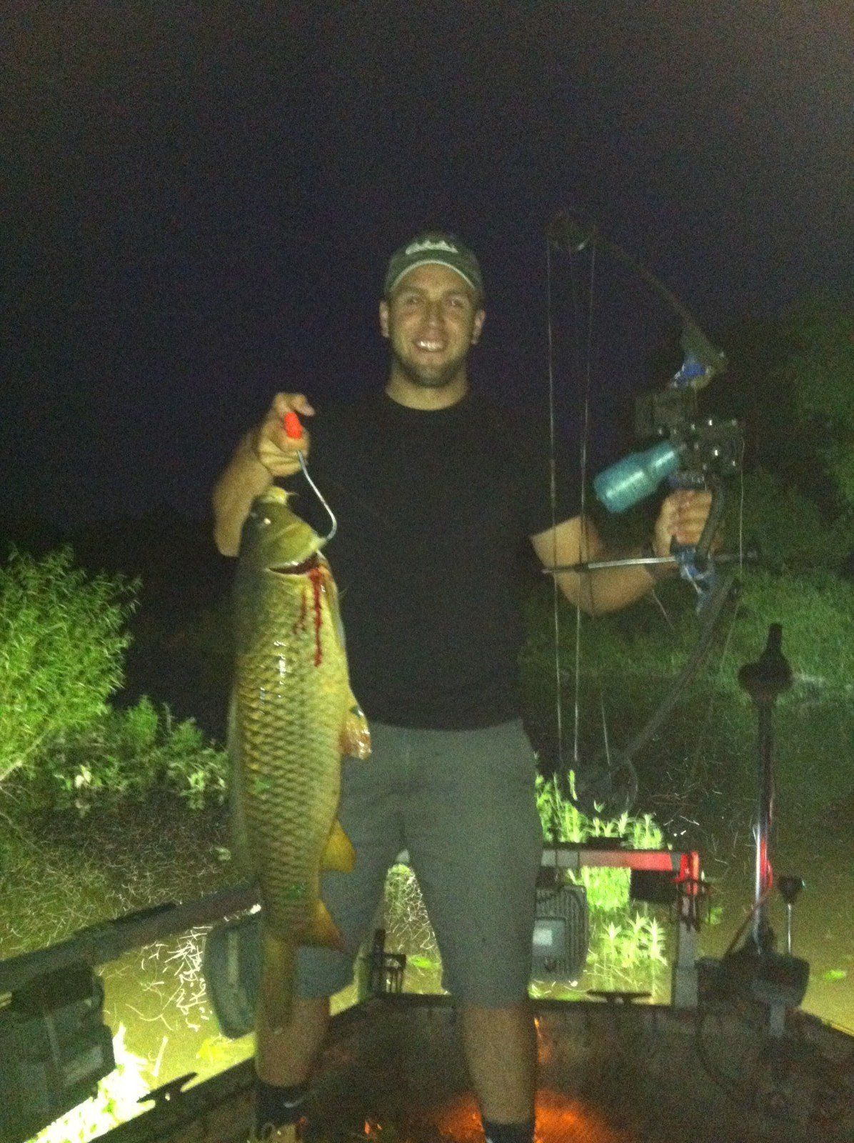 Man in a Boat Holding a Fish and a Bow — Lancaster County, PA — Night Ventures Bowfishing Charters