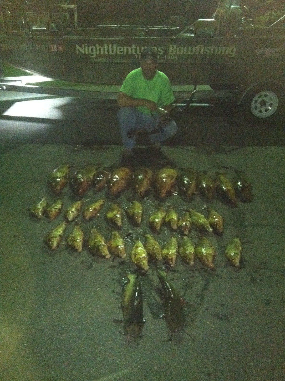 Man Wearing Green Shirt and His Caught Fish Laying on Ground — Lancaster County, PA — Night Ventures Bowfishing Charters