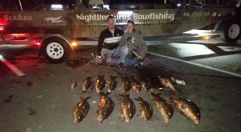 Night Bowfishing — Couple with the Carp Fish on Ground in Lancaster County, PA Night Bowfishing — Couple with the Carp Fish on Ground in Lancaster County, PA
