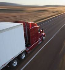 A freight lorry driving down a long road