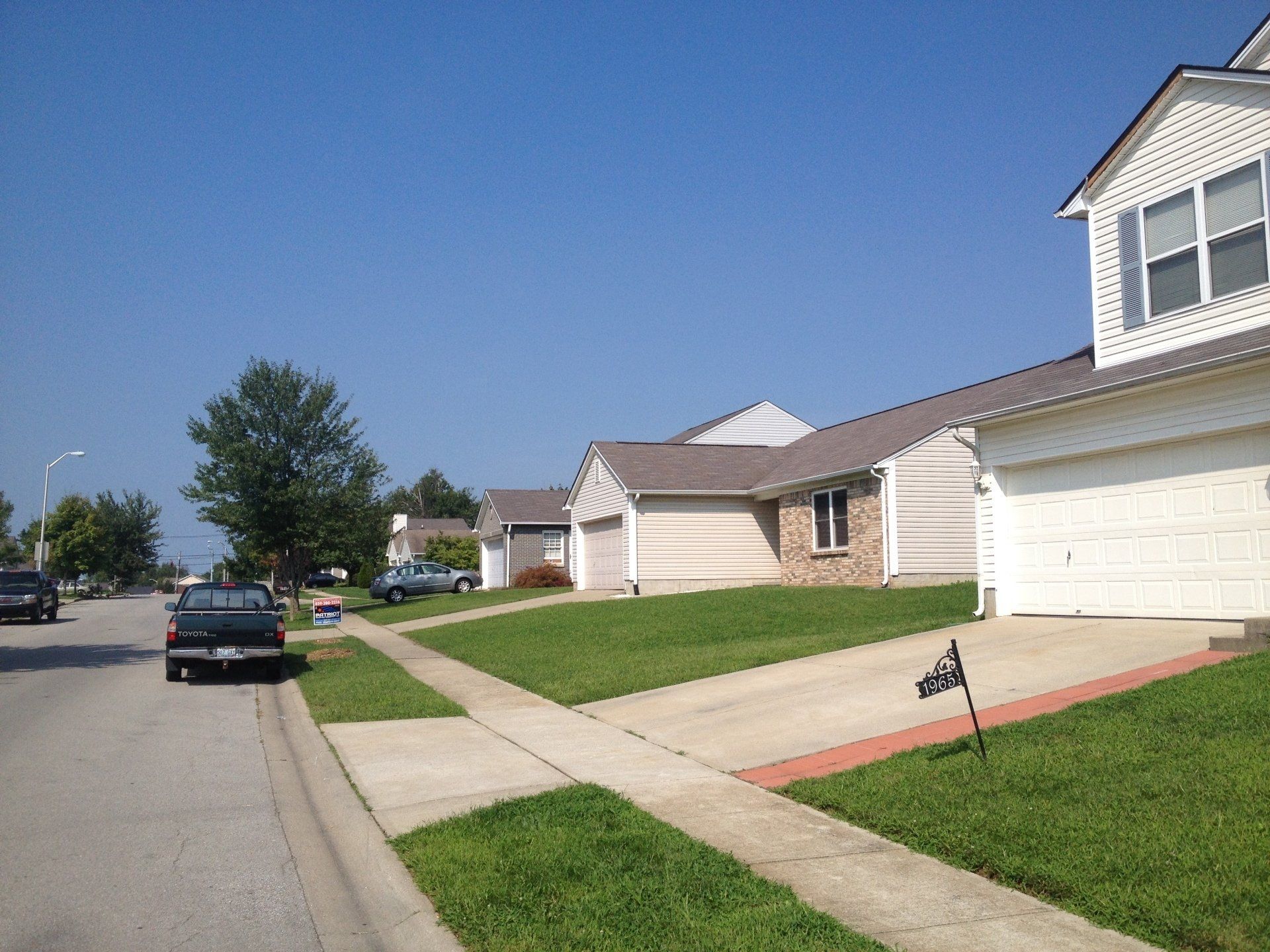 A black truck is parked on the side of the road in front of a house