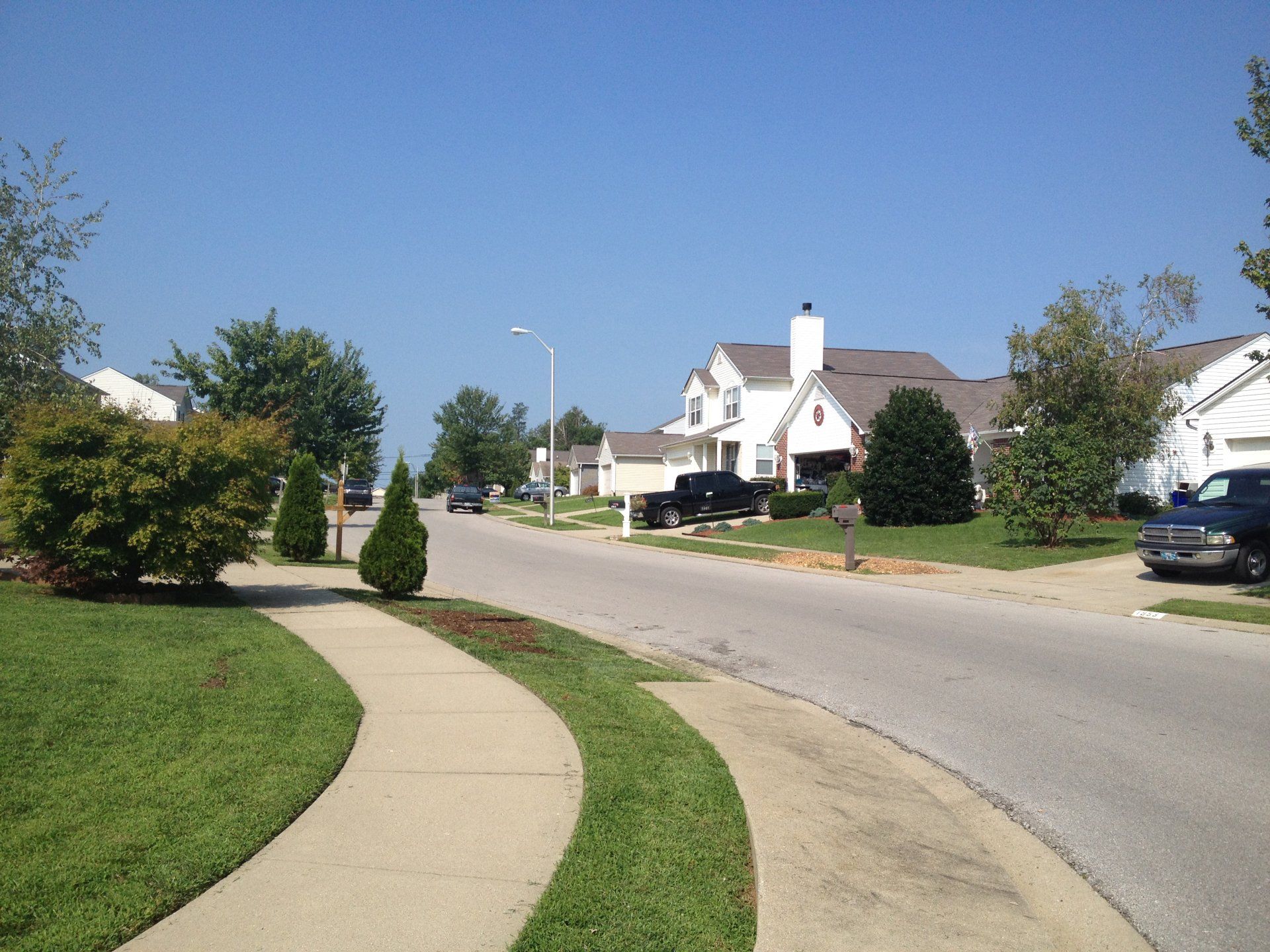 A residential street with cars parked on the side of it