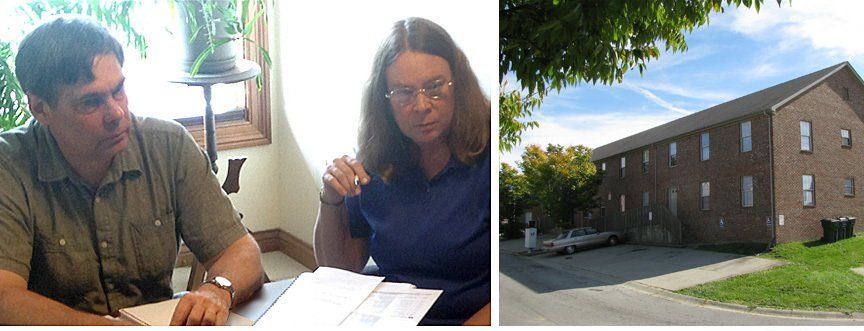 A man and a woman are sitting at a desk in front of a brick building