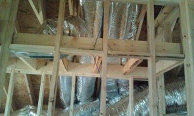 Unfinished attic framing with exposed wooden studs and reflective insulation