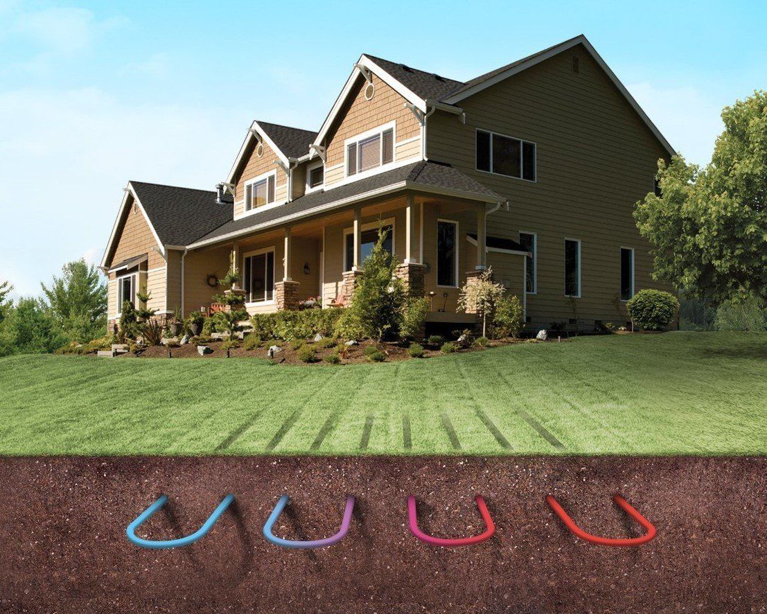 Two-story house with porch and lawn, with blue and red underground pipe markers in the foreground