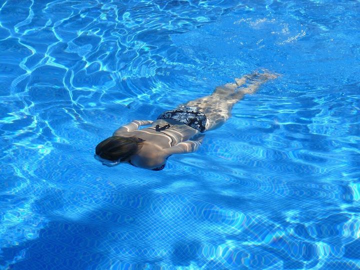 Woman swimming underwater in clear blue pool in chandler