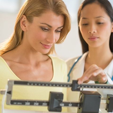 Doctor Weighing Woman on Balance Weight Scale — Hampton, VA — Doctors Weight Loss Clinic Doctor Weighing Woman on Balance Weight Scale — Hampton, VA — Doctors Weight Loss Clinic