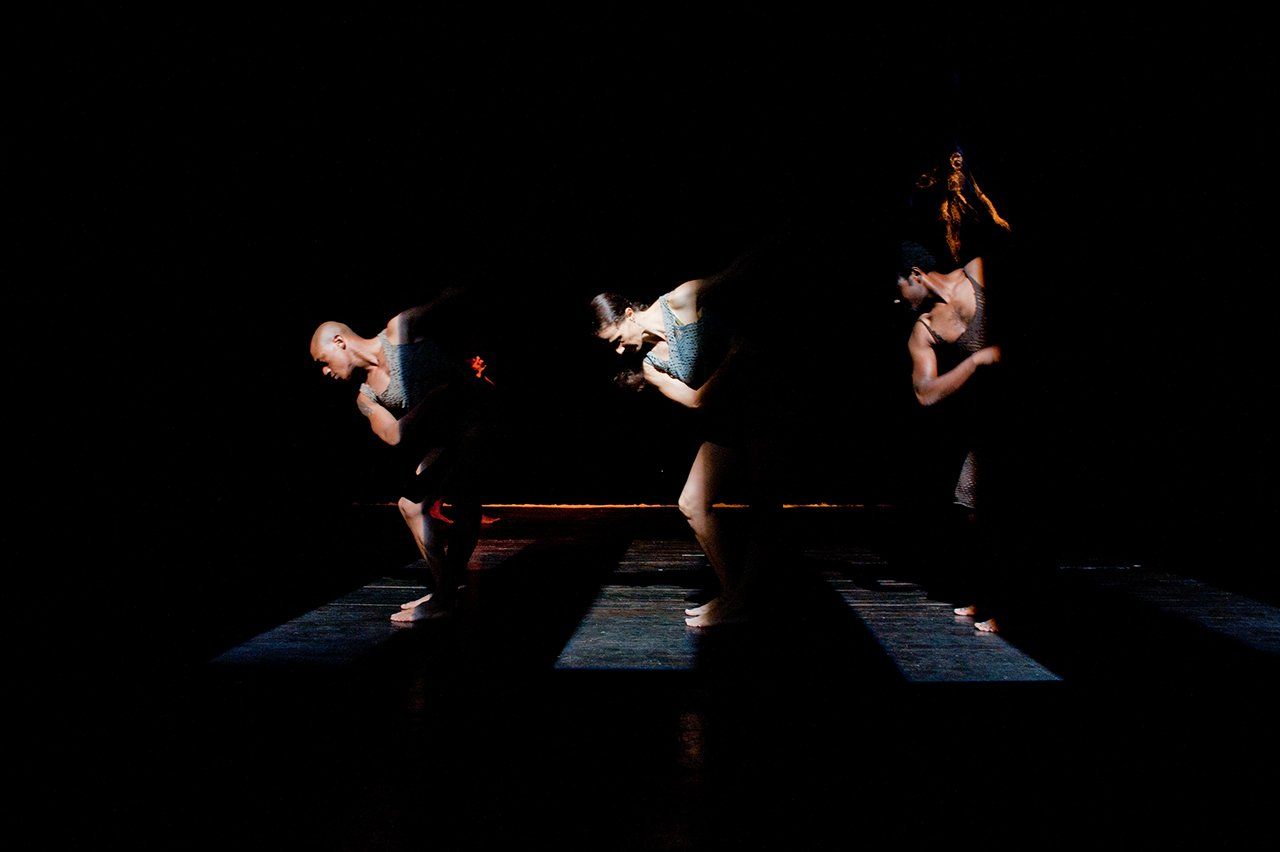 trois danseurs derrière des pilônes noirs