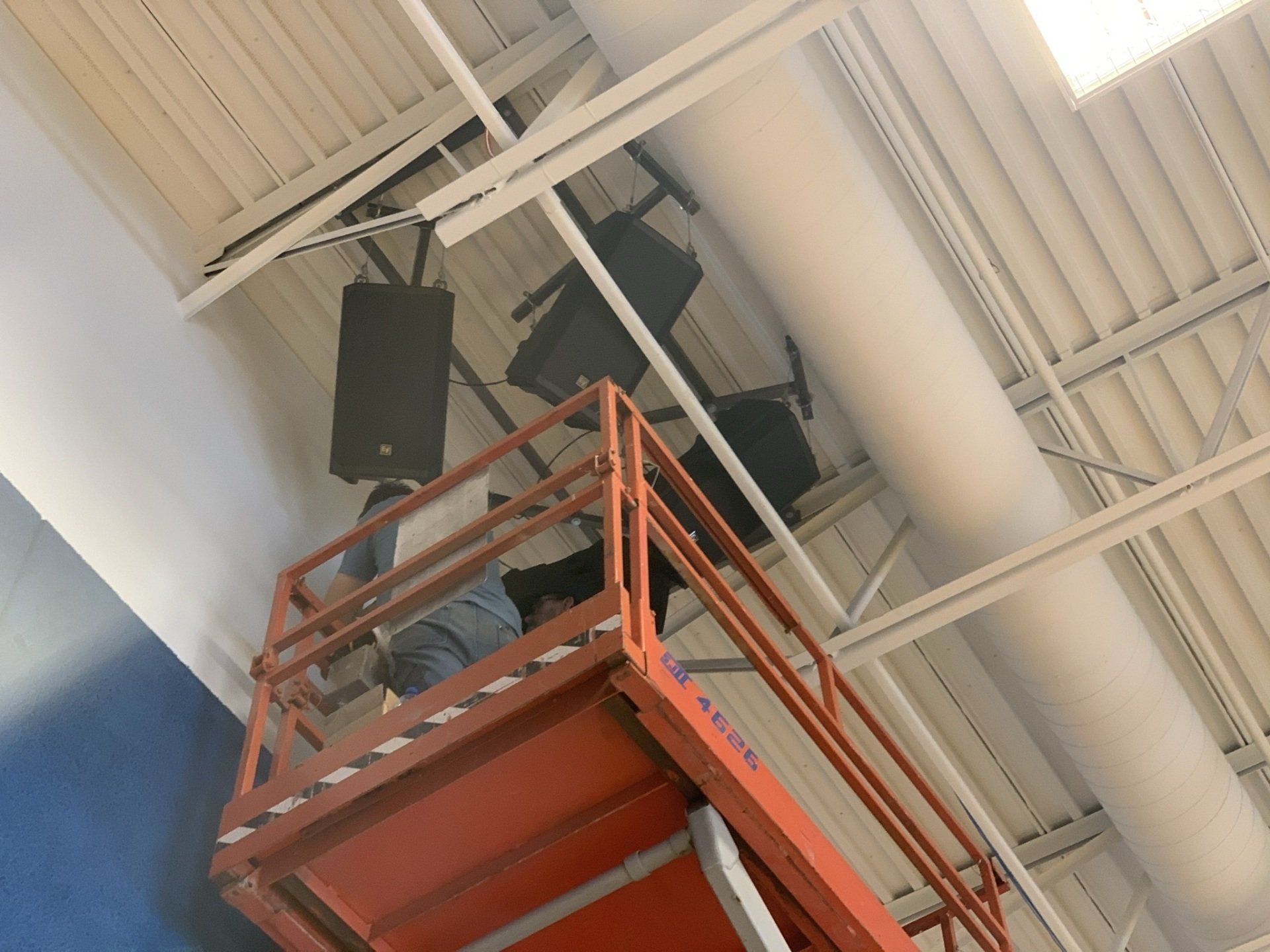 A man is standing on a lift looking up at the ceiling.