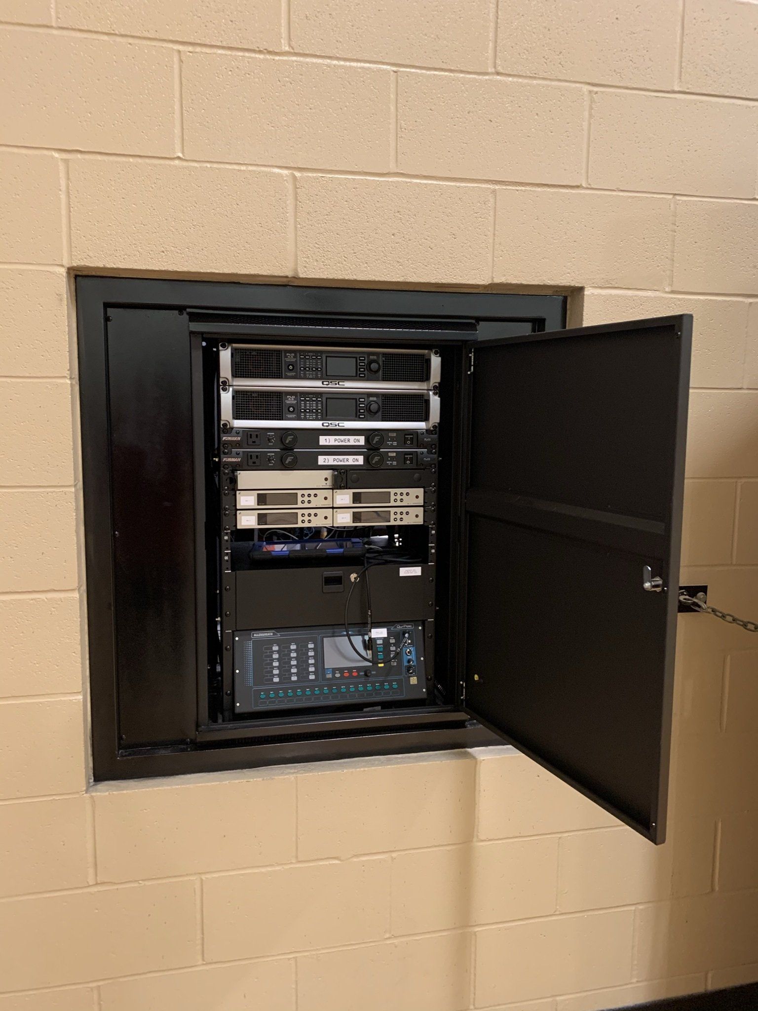 A brick wall with a black cabinet with the door open