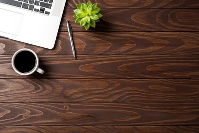A laptop, coffee,succulent, and pen on a wood desk