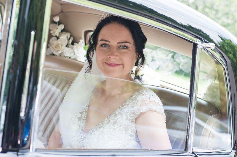 bride sitting in wedding car with bridal hair and airbrush makeup by Jax-Glam Beauty Bristol