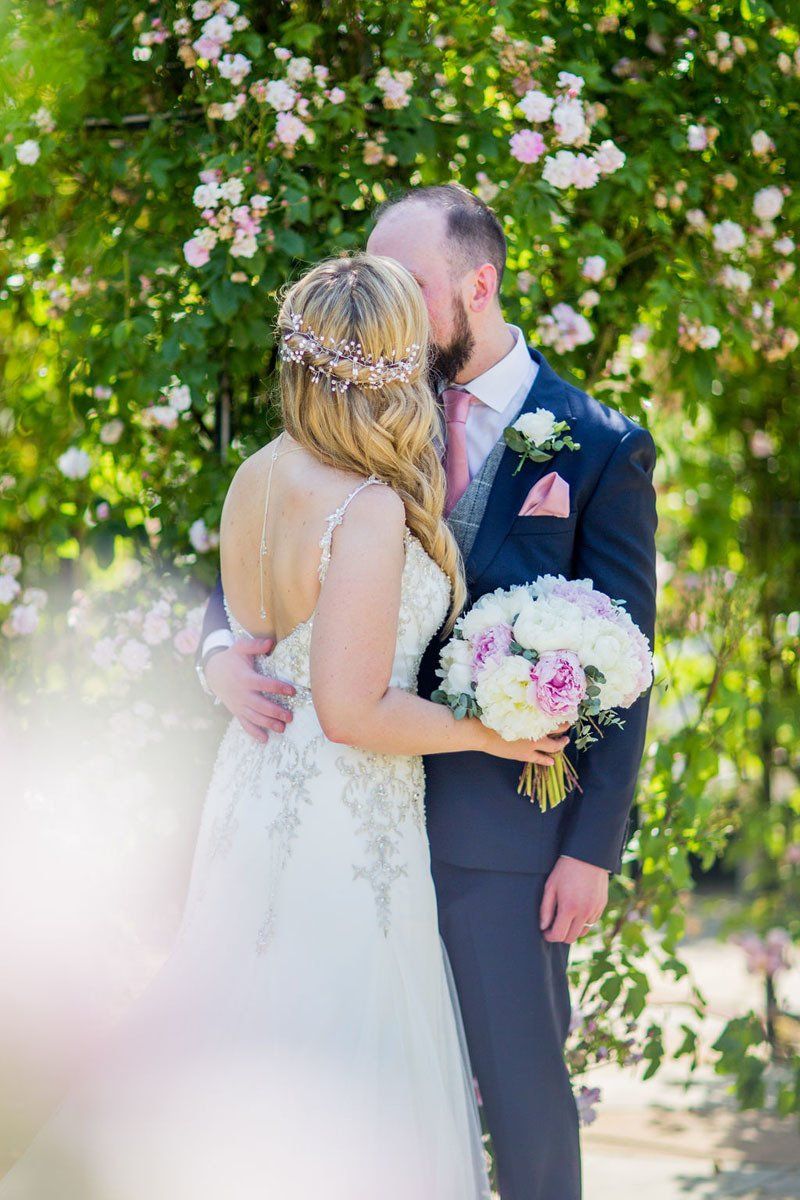 bride and groom portrait with floral backdrop and bridal makeup by Jax-Glam Beauty Bristol