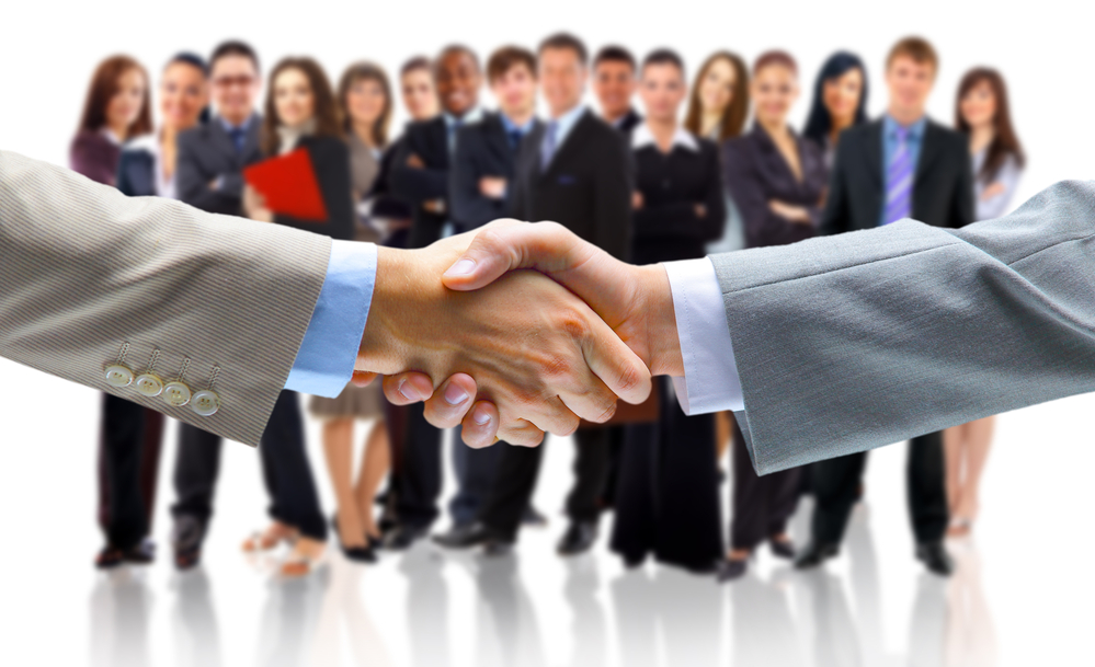 two people shaking hands with a crowd of people in the background
