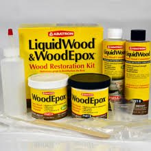 A wood restoration kit including a yellow box, bottles, jars, and tools.