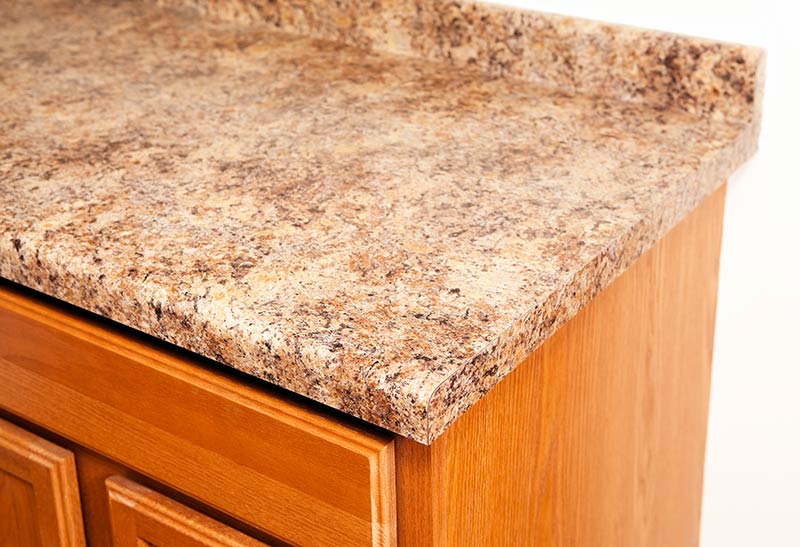 Close-up of a wooden cabinet with a speckled brown countertop.