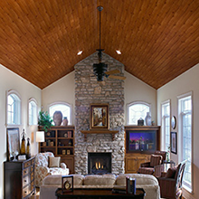 Living room with a stone fireplace, wood ceiling, and neutral-colored walls.
