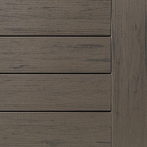 Close-up of weathered gray composite decking planks with a contrasting vertical trim piece.