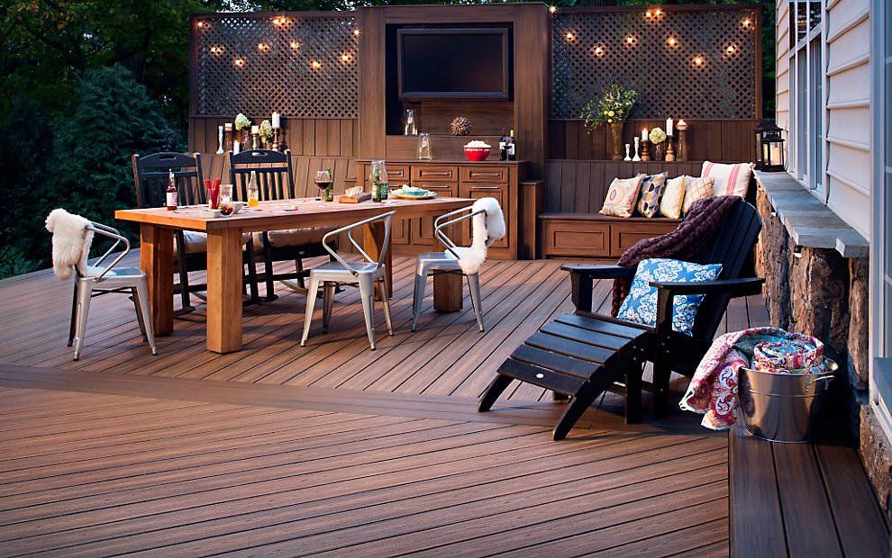Outdoor deck with dining table, seating, and built-in entertainment area at dusk.