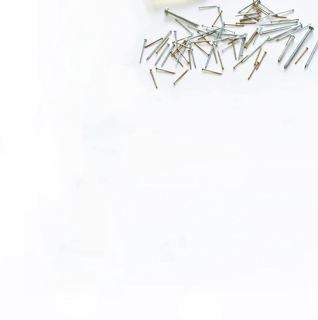 Scattered small silver nails on a white surface.