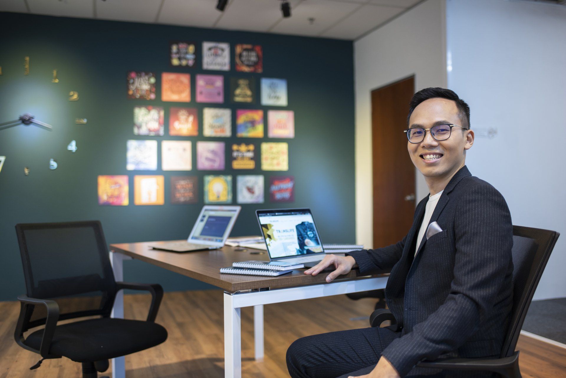 A man in a suit is sitting at a desk with a laptop.