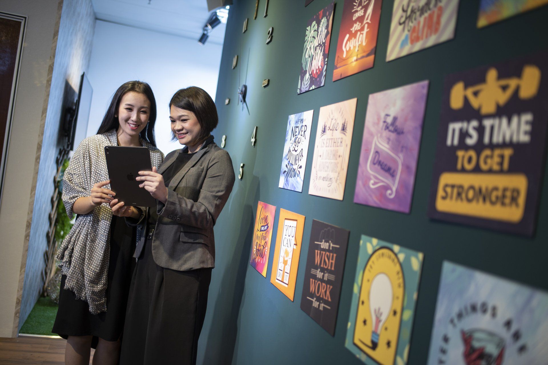 Two women are standing in front of a wall with posters on it.