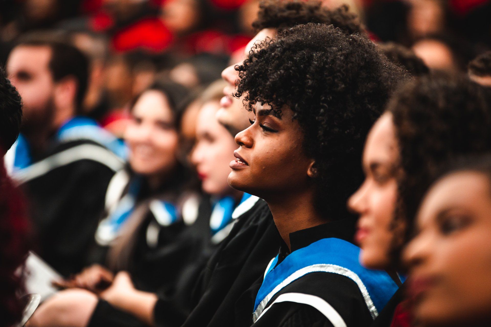 A group of people are sitting in a row at a graduation ceremony.