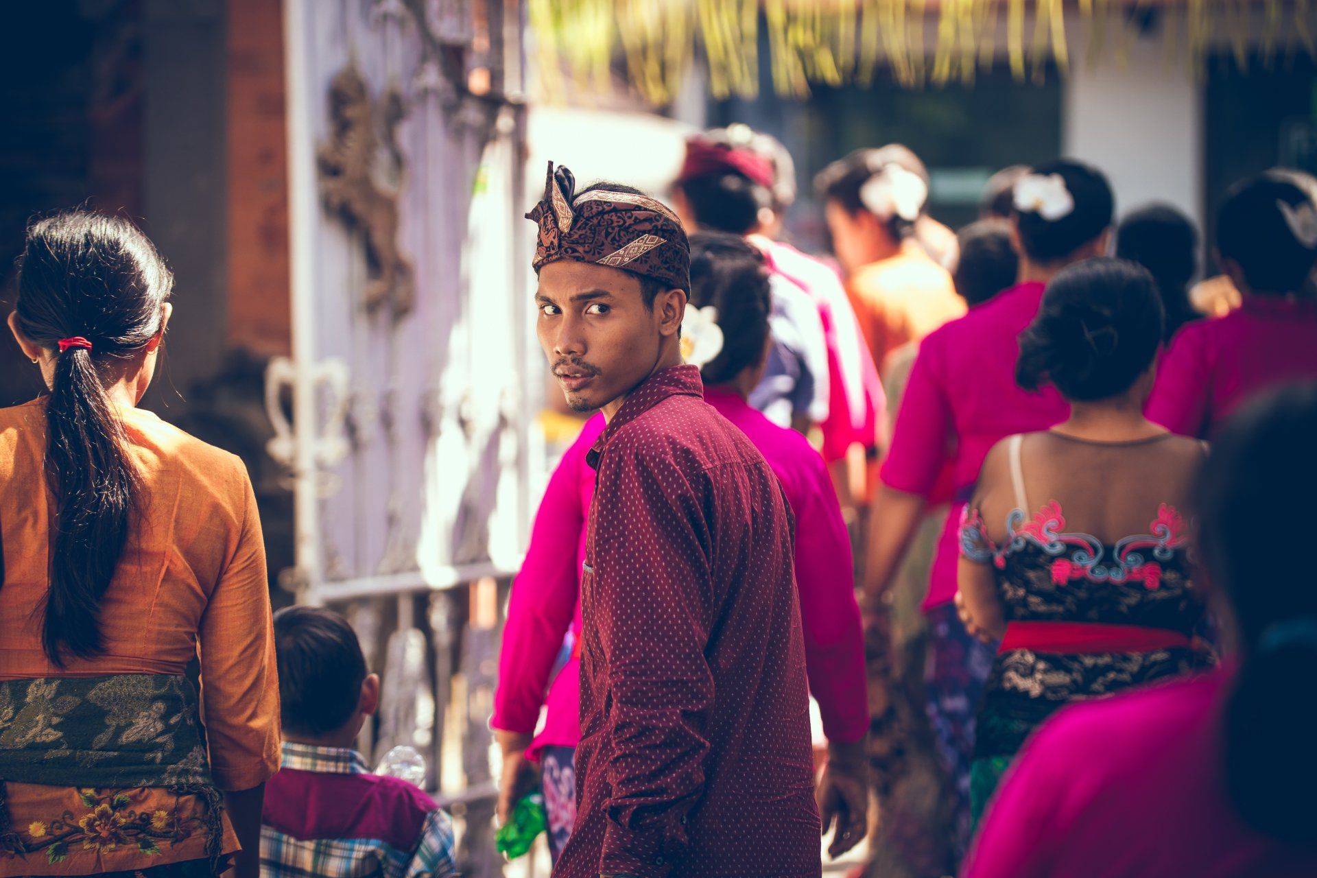 Photo by Artem Bali A man in a red shirt is standing in a crowd of people.