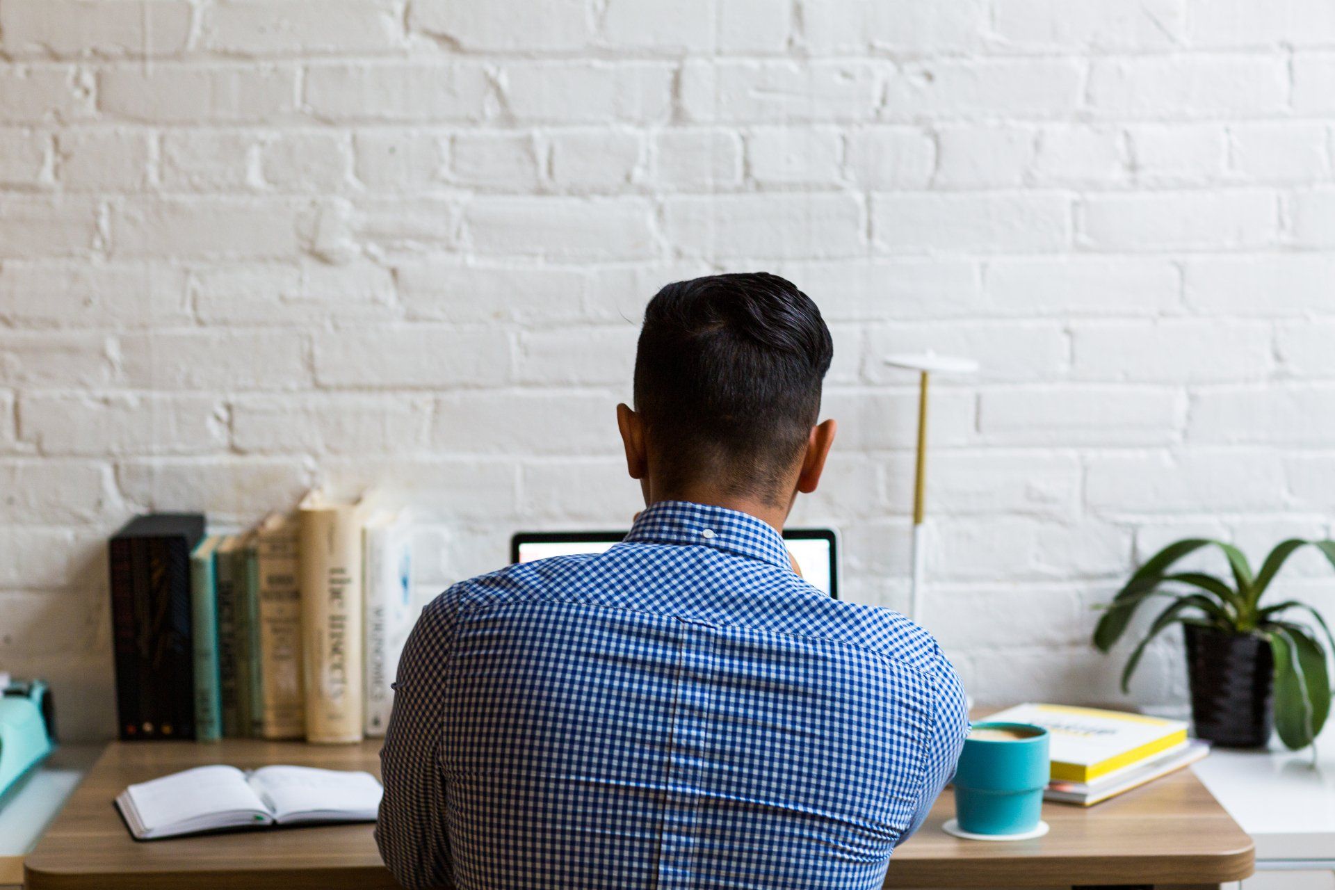 A man is sitting at a desk using a laptop computer.