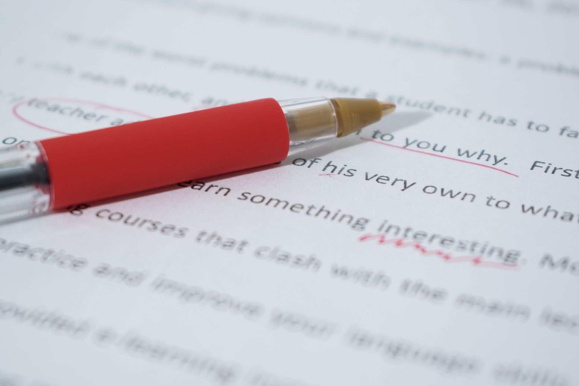 A red pen is sitting on top of a piece of paper.