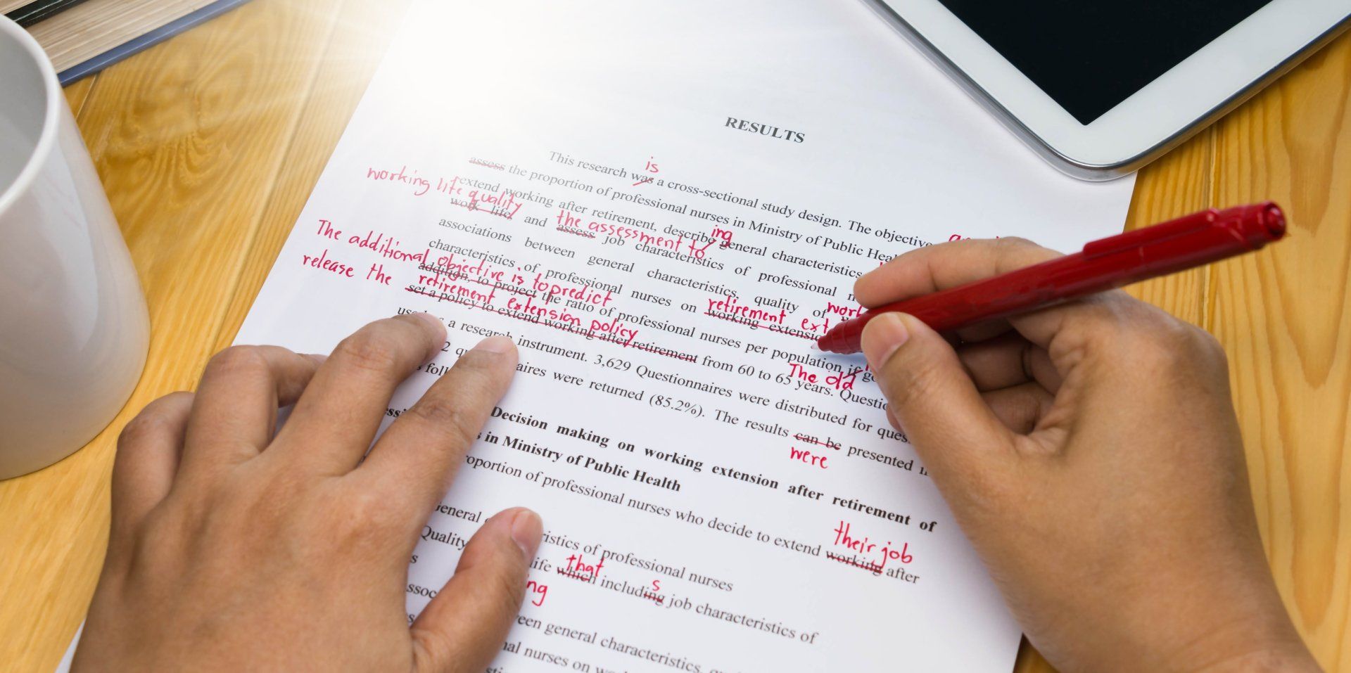 A person is editing a piece of paper with a red pen.