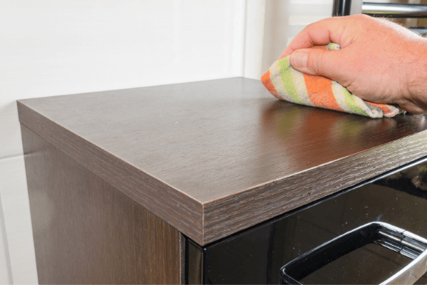 A hand wiping the top of an office filing cabinet for janitorial services