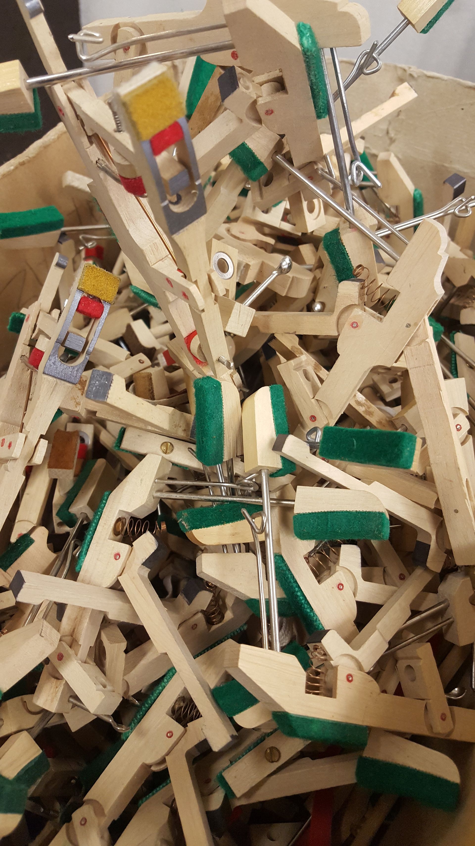 Ein Haufen zerbrochener beiger und grüner Holzspielzeugteile und -latten, die sich in einem Behälter verheddert hatten.