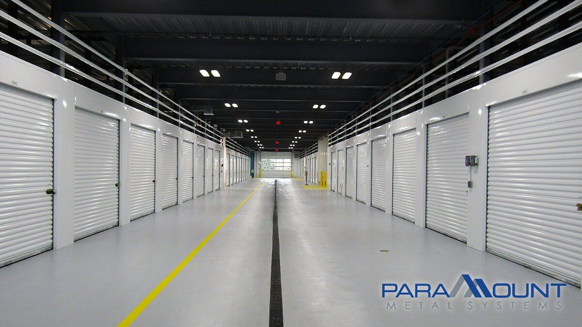 Interior of a storage facility with a long hallway lined with white storage unit doors.