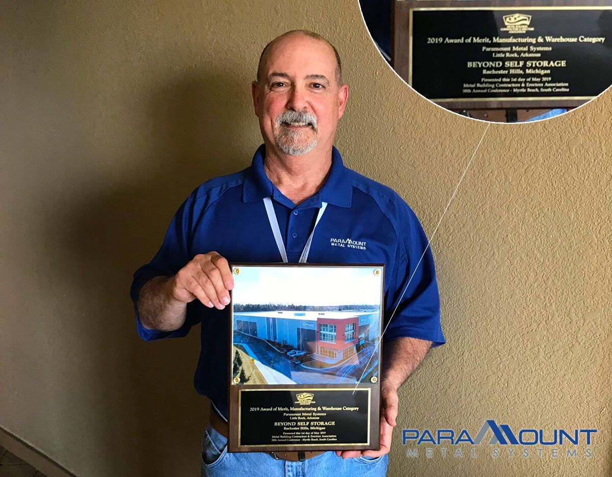Man holding award plaque with a train image. A second plaque inset.