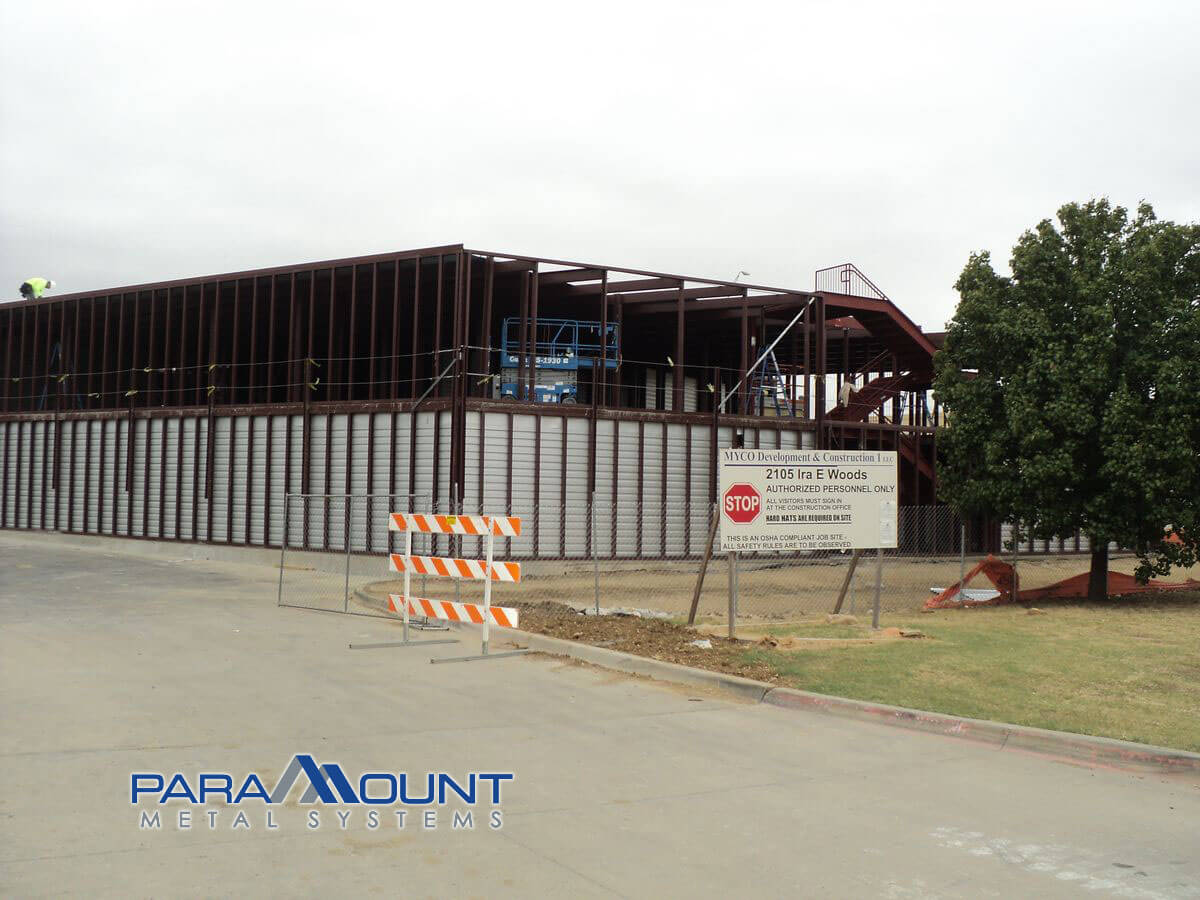 Construction site: steel frame building, temporary barriers, sign.