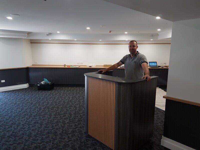 Man Standing At Reception Desk — DMB Kitchens in Port Macquarie, NSW